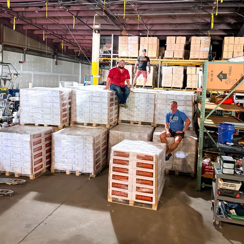 A warehouse aisle filled with shrink-wrapped pallets of LumaNail cases.