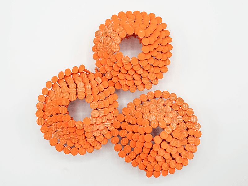 Three coils of LumaNail roofing nails seen head-on, showing the textured waffle pattern across every fluorescent orange head.